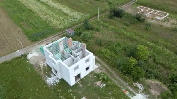Воздушный вид незавершенного каркаса частного дома с легкими газобетонными стенами и строящимися деревянными балками на крыше — стоковое видео