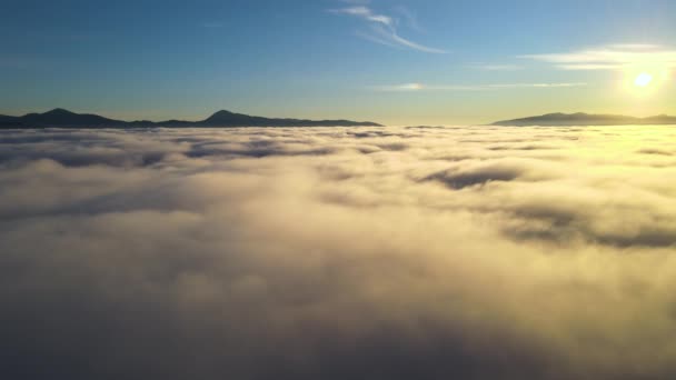Luchtfoto van levendige gele zonsopgang boven witte dichte wolken en verre bergen aan de horizon — Stockvideo