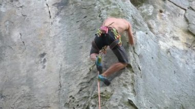 Güçlü erkek tırmanıcı kayalık dağın dik duvarına tırmanıyor. Sporcu zor yolu aştı. Ekstrem spor hobisi konsepti