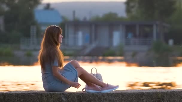 Jovem mulher em roupa casual relaxante no lado do lago na noite quente. férias de verão e conceito de viagem — Vídeo de Stock