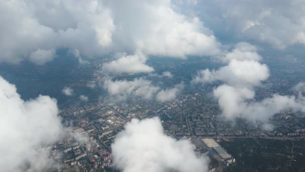 Luchtfoto vanuit vliegtuigraam op grote hoogte van verre stad bedekt met gezwollen cumulus wolken vormen zich voor regenbui — Stockvideo
