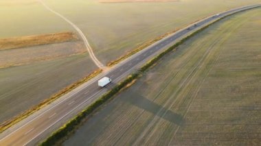 Gün batımında hızlı giden arabalarla şehirlerarası yol manzarası. Akşamları otoban trafiğinin insansız hava aracı görüntüsü
