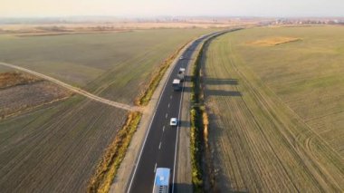 Gün batımında hızlı giden arabalarla şehirlerarası yol manzarası. Akşamları otoban trafiğinin insansız hava aracı görüntüsü