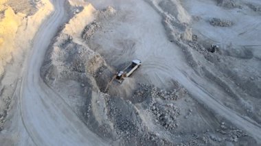 Kazı makineleri ve çöp kamyonlarıyla inşaat endüstrisi için kumtaşı malzemelerinden oluşan açık maden manzarası. Madencilik ve kullanışlı mineral üretiminde ağır ekipman