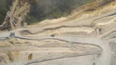 Kazı araçları ve çöp kamyonlarıyla inşaat endüstrisi için kireçtaşı malzemelerinin açık maden sahası görüntüsü