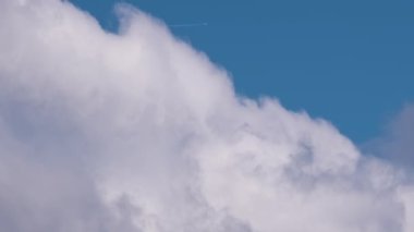 Uzaktaki yolcu uçağı mavi gökyüzünde yüksek irtifada uçarken beyaz bulutlar ardında iz bırakıyor. Hava yolculuğu konsepti