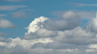 Mavi açık gökyüzünde hızlı hareket eden beyaz kabarık kümülüs bulutlarının hızlandırılmış görüntüleri