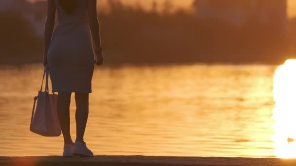 Visão traseira da mulher solitária em pé sozinho na margem do lago na noite quente. Solidão e relaxamento no conceito de natureza — Vídeo de Stock