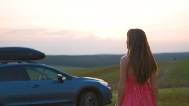 Mujer joven que se relaja sola en el campo verde durante el viaje por carretera en verano. Viajar en coche concepto — Vídeos de Stock