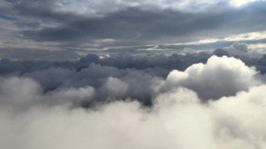 Dünya 'nın yüksek irtifasında, yağmur fırtınasından önce oluşan kabarık kümülüs bulutlarıyla kaplı uçak penceresinden hava görüntüsü
