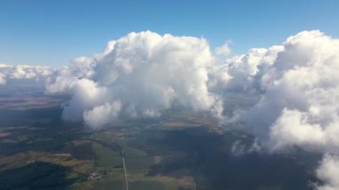 Dünya 'nın yüksek irtifasındaki uçak penceresinden hava manzarası beyaz kabarık kümülüs bulutlarıyla kaplı.