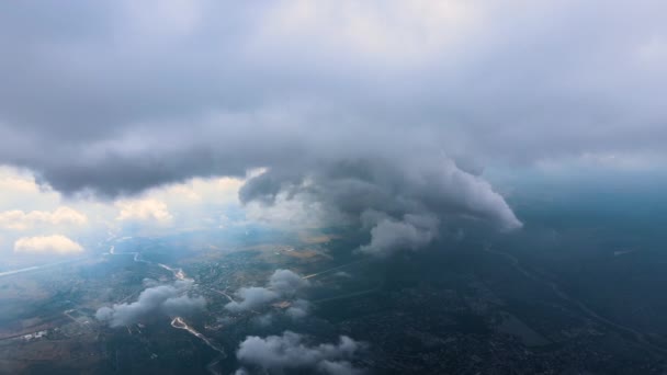 Luftaufnahme aus dem Flugzeugfenster in großer Höhe einer weit entfernten Stadt, die vor einem Regensturm mit geschwollenen Kumuluswolken bedeckt ist — Stockvideo