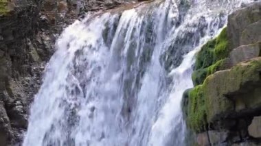Yazın yağmur ormanlarında kayalık kayalıklardan dökülen beyaz köpüklü suyla dağ nehrindeki muhteşem şelale manzarası.