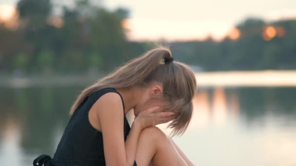 Jovem deprimida sentada sozinha ao ar livre chorando tristemente. Conceito de depressão e emoções — Vídeo de Stock