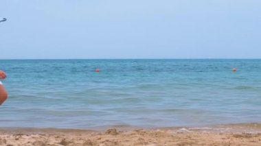 Yaz tatillerinde deniz kıyısında kumsalda yürüyen beyaz elbiseli mutlu bir kız çocuğu. Tatil konseptinde seyahat ve dinlenme