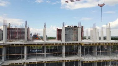 İnşaat halindeki yüksek beton binadaki vinç ve işçiler. Gayrimenkul geliştirme kavramı