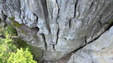 Küçük çocuk kayalık dağın dik duvarına tırmanıyor. Çocuk tırmanışçı zorlu rotayı aştı. Ekstrem spor konseptine dalmak