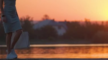 Sıcak bir akşamda gölün kıyısında tek başına yürüyen genç bir kadın. Yalnızlık ve doğa konseptinde rahatlama.