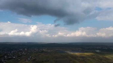 Yükseklerdeki uçak penceresinden, yağmurdan önce oluşan kabarık kümülüs bulutlarıyla kaplı uzak şehrin hava manzarası.