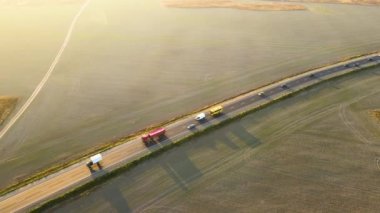 Gün batımında hızlı giden arabalarla şehirlerarası yol manzarası. Akşamları otoban trafiğinin insansız hava aracı görüntüsü