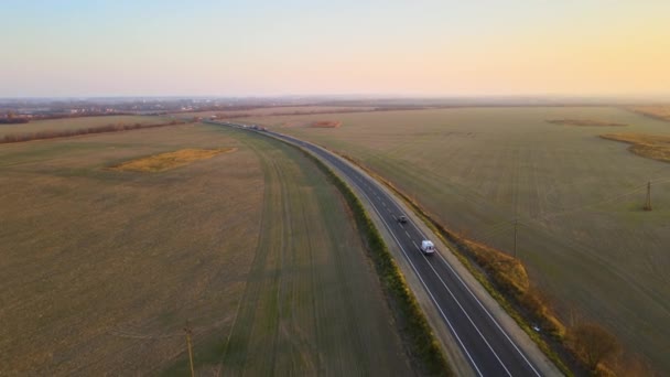 Widok z lotu ptaka na międzymiastową drogę z szybkimi samochodami o zachodzie słońca. Widok z góry z drona ruchu drogowego w godzinach wieczornych — Wideo stockowe