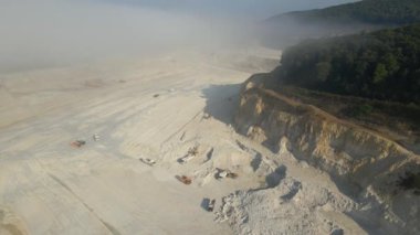 Kazı araçları ve çöp kamyonlarıyla inşaat endüstrisi için kireçtaşı malzemelerinin açık maden sahası görüntüsü