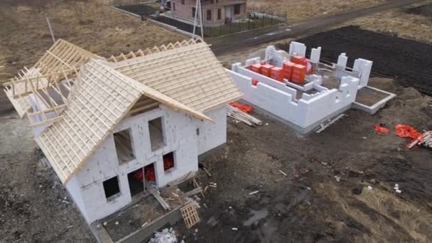 Aerial view of unfinished frame of private house with aerated lightweight concrete walls and wooden roof frame under construction — Stock Video