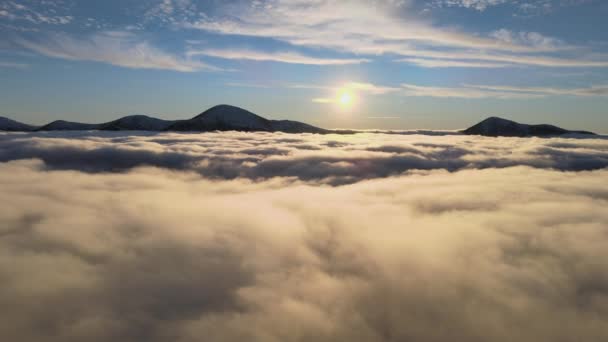 Вид с воздуха на яркий восход солнца над белым плотным туманом с далекими темными вершинами Карпатских гор на горизонте — стоковое видео