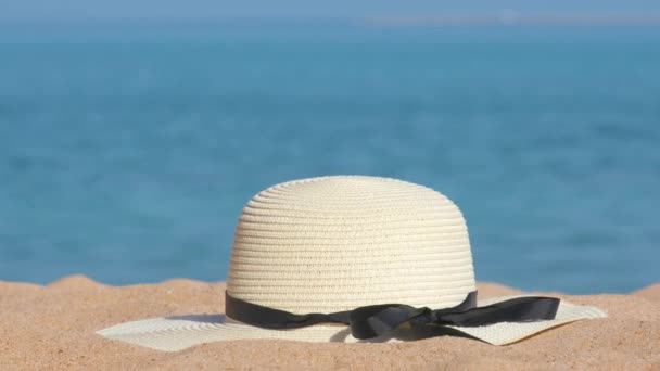 Detailní záběr žluté slaměné čepice na písečné pláži u tropického moře za teplého slunečného dne. Koncept letních prázdnin — Stock video