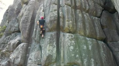 Kararlı dağcı kayalık dağın dik duvarına tırmanıyor. Sporcu zor yolu aştı. Ekstrem sporlar ve kaya tırmanışı hobileri.