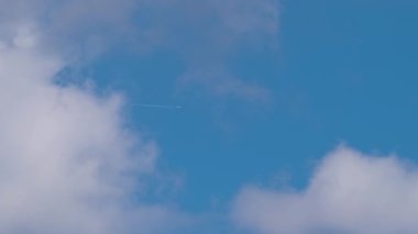 Uzaktaki yolcu uçağı mavi gökyüzünde yüksek irtifada uçarken beyaz bulutlar ardında iz bırakıyor. Hava yolculuğu konsepti