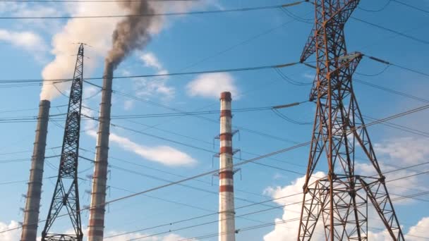 Wysokonapięciowe słupy elektryczne przeciwko wysokonapięciowej elektrowni węglowej wysokie rury z czarnym dymem poruszającym się w górę zanieczyszczającą atmosferę. Produkcja energii elektrycznej z zastosowaniem koncepcji paliw kopalnych — Wideo stockowe