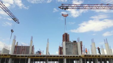 İnşaat halindeki yüksek beton binadaki vinç ve işçiler. Gayrimenkul geliştirme kavramı