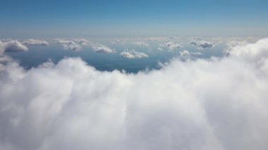 Dünya 'nın yüksek irtifasındaki uçak penceresinden hava manzarası beyaz kabarık kümülüs bulutlarıyla kaplı.