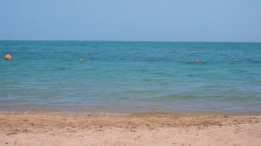 Mavi deniz suyunun yüzeyi ve küçük dalgalı dalgaların sarı kumsala çarptığı deniz burnu. Seyahat ve tatil kavramı