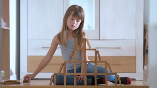 Glad barn flicka spelar jenga spel stapling trä leksaksblock i hög lugg struktur. Handrörelsekontroll och uppbyggnad av beräkningsfärdigheter — Stockvideo