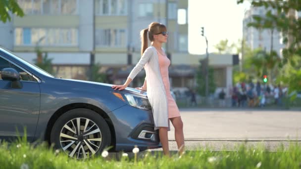 Happy woman driver in casual outfit enjoying warm day near her car on a summer street. Travel and transportation concept — Stock Video