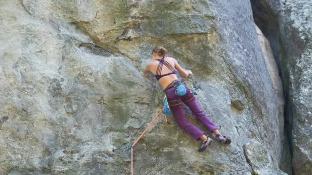 Starke Bergsteigerin klettert steile Felswand hinauf. Sportlerin bewältigt schwierige Strecke. Engagement im Extremsport Hobby-Konzept — Stockvideo