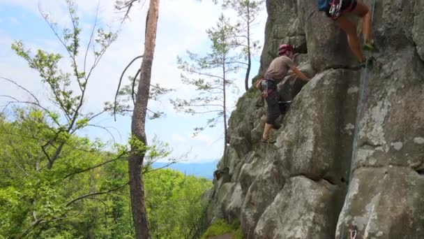 Escalador masculino fuerte escalando empinada pared de montaña rocosa. Deportista superando ruta difícil. Participar en el concepto de pasatiempo deportivo extremo — Vídeo de stock