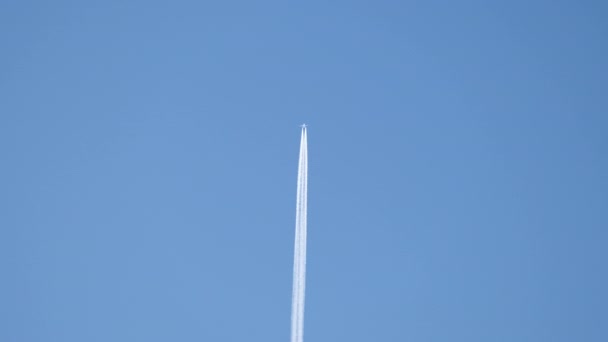 Віддалений пасажирський реактивний літак летить на великій висоті на ясному блакитному небі, залишаючи білий дим слідом за контрактом. Концепція авіаперевезень — стокове відео