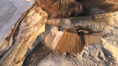 Kazı makineleri ve çöp kamyonlarıyla inşaat endüstrisi için kumtaşı malzemelerinden oluşan açık maden manzarası. Madencilik ve kullanışlı mineral üretiminde ağır ekipman