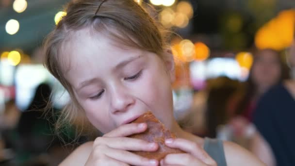 Παιδί κορίτσι τρώει νόστιμο burger στο εστιατόριο — Αρχείο Βίντεο