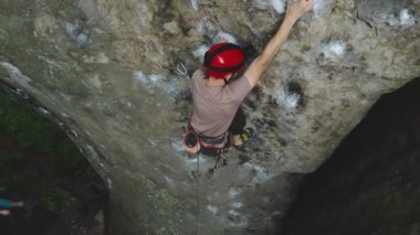 Güçlü erkek tırmanıcı kayalık dağın dik duvarına tırmanıyor. Sporcu zor yolu aştı. Ekstrem spor hobisi konsepti