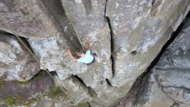 Küçük çocuk kayalık dağın dik duvarından aşağı iniyor. Çocuk tırmanışçı zorlu rotayı aştı. Ekstrem spor konseptine dalmak