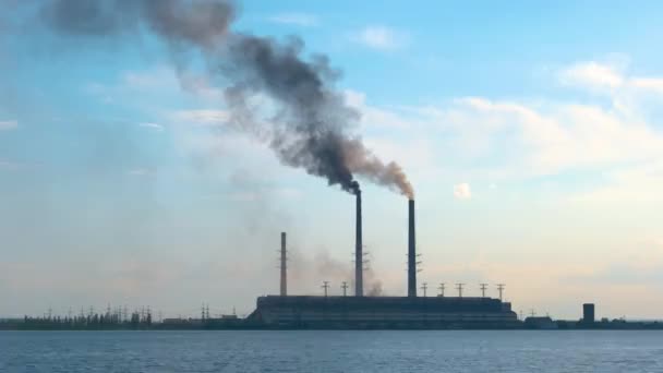 Elektrownia węglowa wysokie rury z czarnym dymem poruszające się w górę zanieczyszczającą atmosferę nad wodą jeziorną — Wideo stockowe