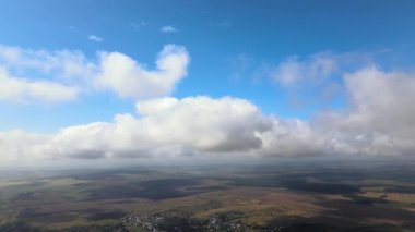 Dünya 'nın yüksek irtifasındaki uçak penceresinden hava manzarası beyaz kabarık kümülüs bulutlarıyla kaplı.