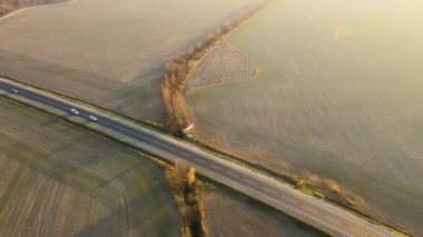 Gün batımında hızlı giden arabalarla şehirlerarası yol manzarası. Akşamları otoban trafiğinin insansız hava aracı görüntüsü