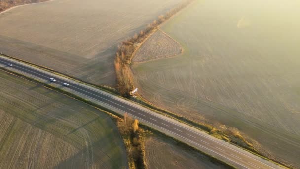 Widok z lotu ptaka na międzymiastową drogę z szybkimi samochodami o zachodzie słońca. Widok z góry z drona ruchu drogowego w godzinach wieczornych — Wideo stockowe