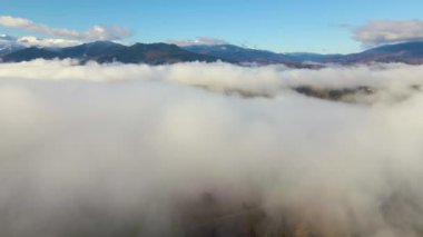 Dağ tepelerinin havadan görünüşü ladin ormanlarıyla kaplıydı ve parlak güneşli bir günde yukarıda beyaz, yoğun bulutlar vardı.