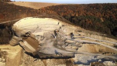 Kazı makineleri ve çöp kamyonlarıyla inşaat endüstrisi için kumtaşı malzemelerinden oluşan açık maden manzarası. Madencilik ve kullanışlı mineral üretiminde ağır ekipman